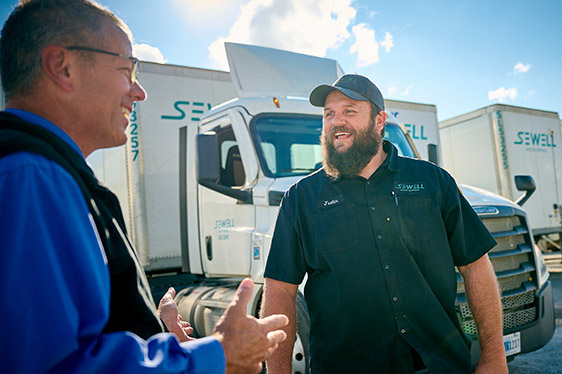 Two Sewell Motor Express employees happily chatting in the truck yard.